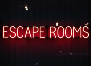 The word Escape Room is lit up in neon lights