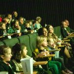 Children watch from the cinema seats as their work is shown on the screen