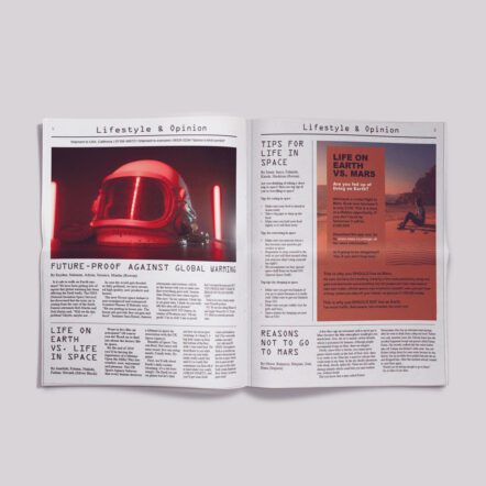 A newspaper lays spread out on a grey background. The articles feature a new space helmet and an advert about life on mars. 