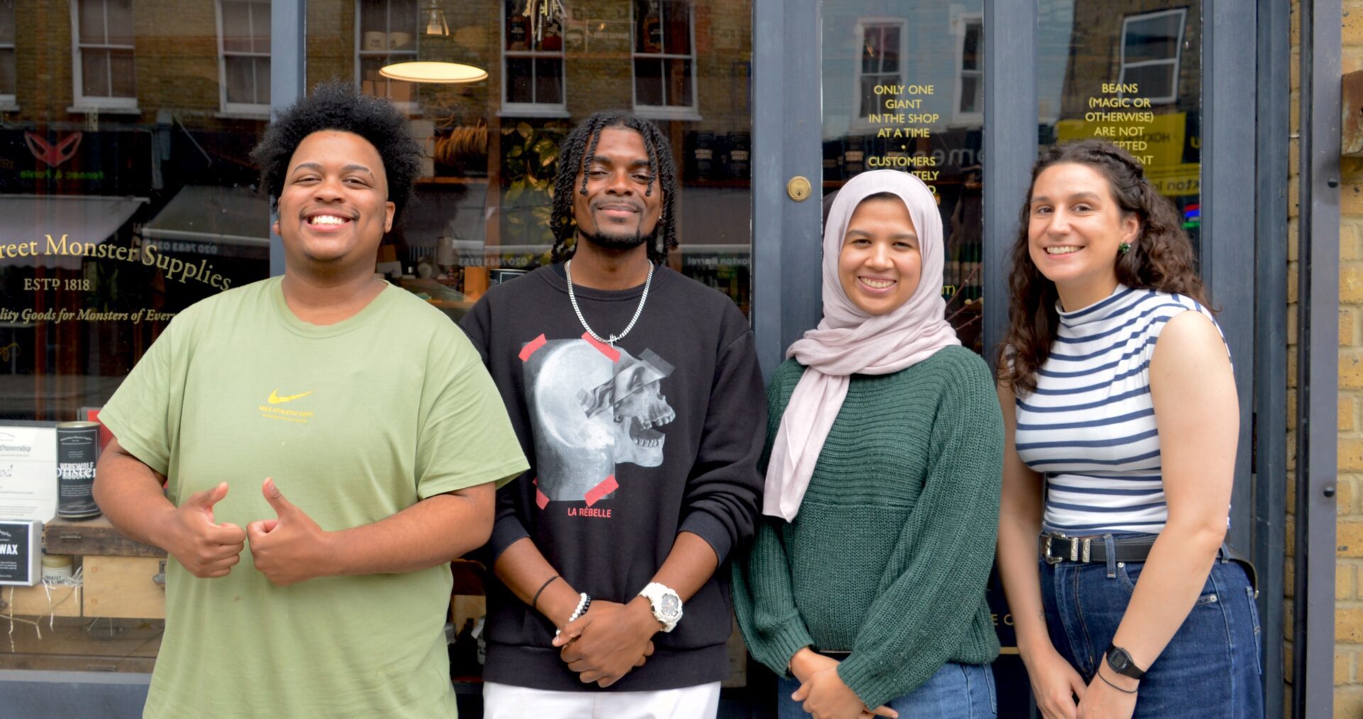 Four smiling young adults stand outside the front of Ministry of Stories on Hoxton road.