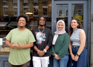 Four smiling young adults stand outside the front of Ministry of Stories on Hoxton road.